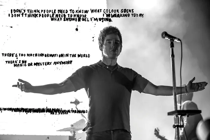 Noel Gallagher singing on stage with arms outstretched
