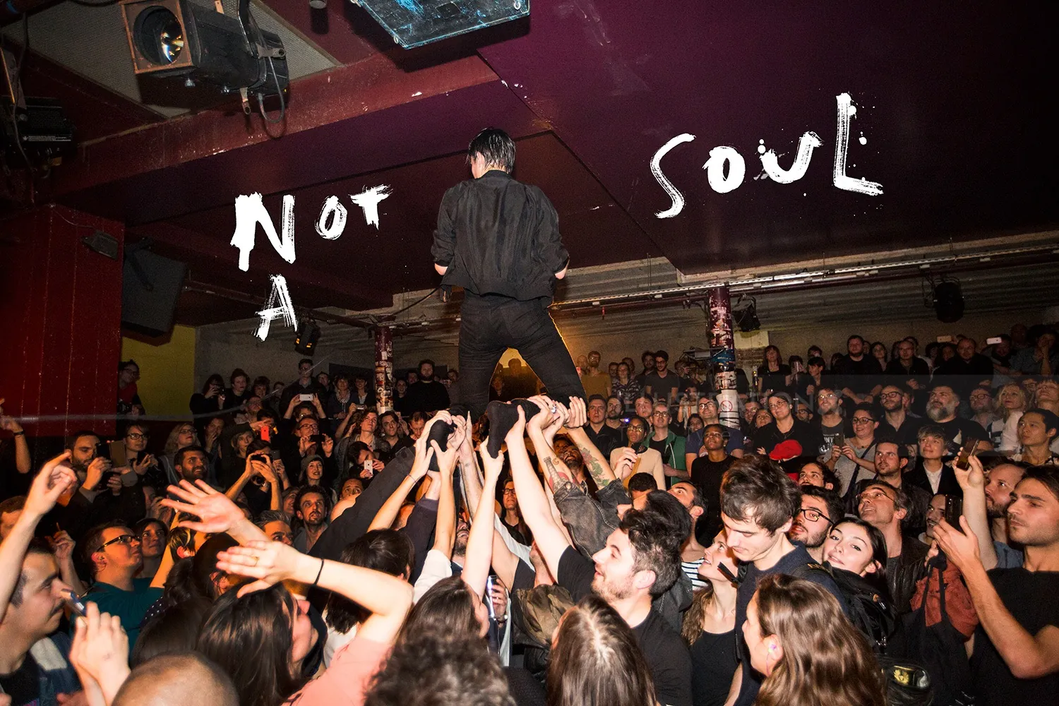 Man standing on crowd's hands at lively concert