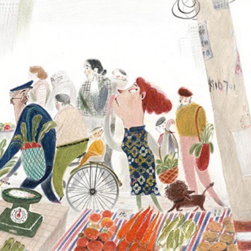 People walking by a market stall with various goods displayed.