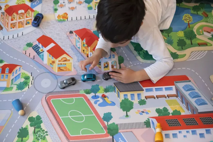 Child playing with toy cars on a colorful community play mat