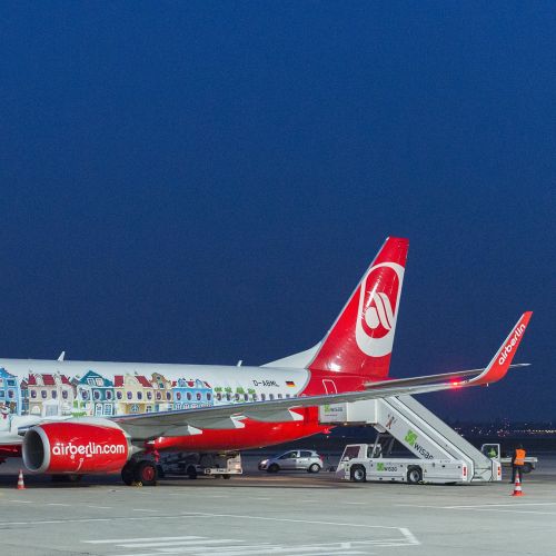 Airplane with colorful artwork parked at airport at night by Thies Schwarz