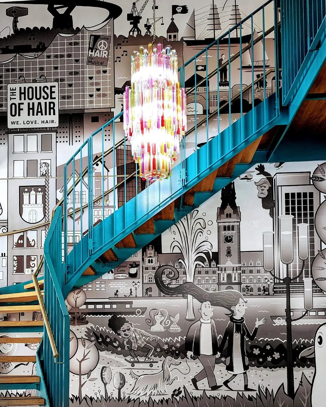 Blue spiral staircase with colorful chandelier and mural background