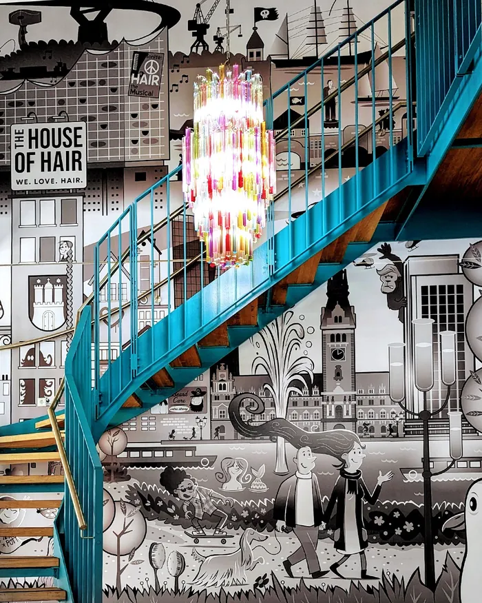 Blue spiral staircase with colorful chandelier and mural background