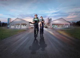 Two workers walking on road near industrial sheds by Tom Krieger