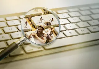 Miniature people on keyboard seen through magnifying glass by Tom Krieger