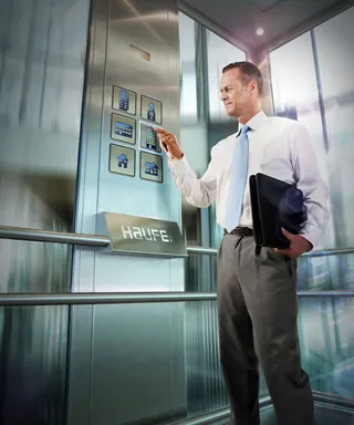 Businessman pressing elevator buttons holding folder by Tom Krieger