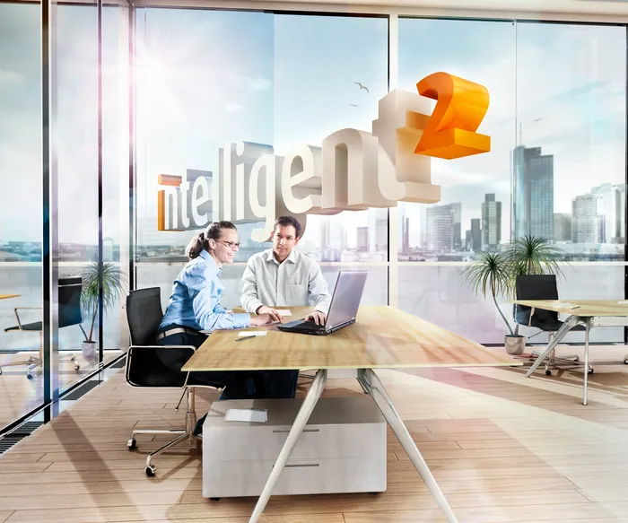Two professionals working together in a modern office with city views by Tom Krieger