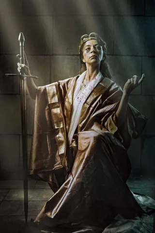 Bronze statue of a woman holding a staff, lit by beams of light, by Tom Krieger