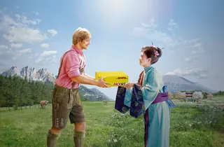 A man in traditional clothes handing a yellow gift box to a woman in a blue kimono by Tom Krieger