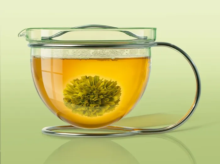 Glass teapot with blooming tea flower in hot water by Tom Krieger