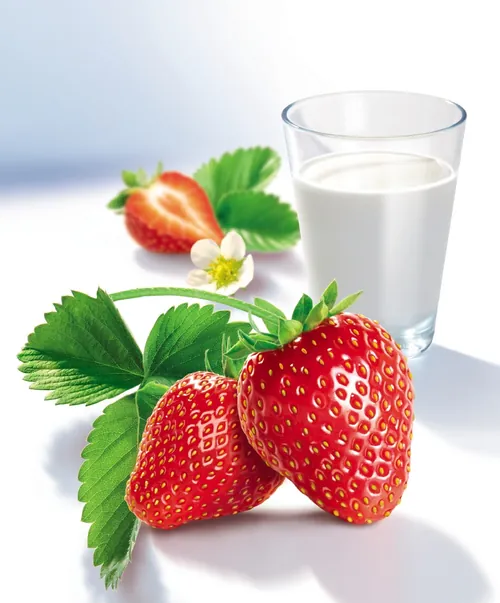Fresh strawberries with green leaves and milk glass by Tom Ungemach
