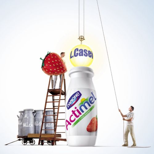 Strawberry being lifted above Actimel bottle by man pulling rope, artwork by Tom Ungemach