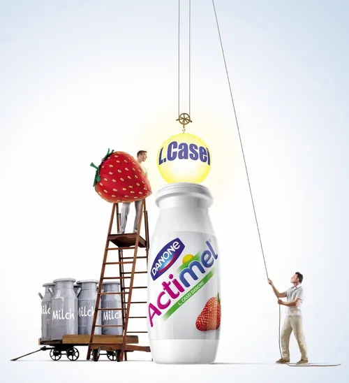 Strawberry being lifted above Actimel bottle by man pulling rope, artwork by Tom Ungemach
