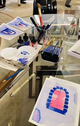 Watercolor painting setup with brushes, paints, and a bottle by Veronica Collignon
