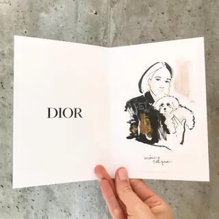Hand holding Dior card with woman and dog sketch by Veronica Collignon