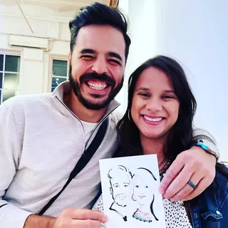 Smiling couple holding caricature drawing by Veronica Collignon