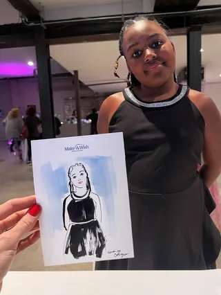 Girl in black dress posing with a caricature sketch of herself