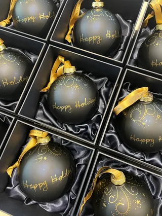 Black Christmas ornaments with gold Happy Holidays text in black boxes