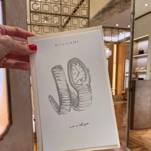 Hand holding Bulgari watch ad card inside elegant boutique