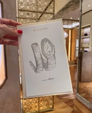 Hand holding Bulgari watch ad card inside elegant boutique