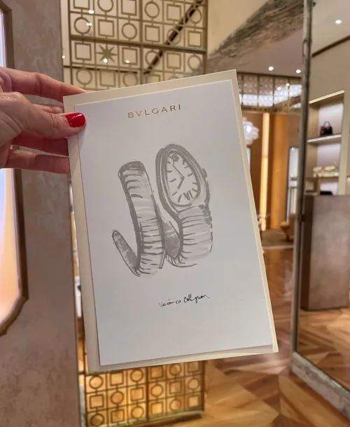 Hand holding Bulgari watch ad card inside elegant boutique