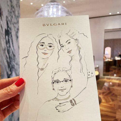 Hand holding a BVLGARI illustration of three faces indoors