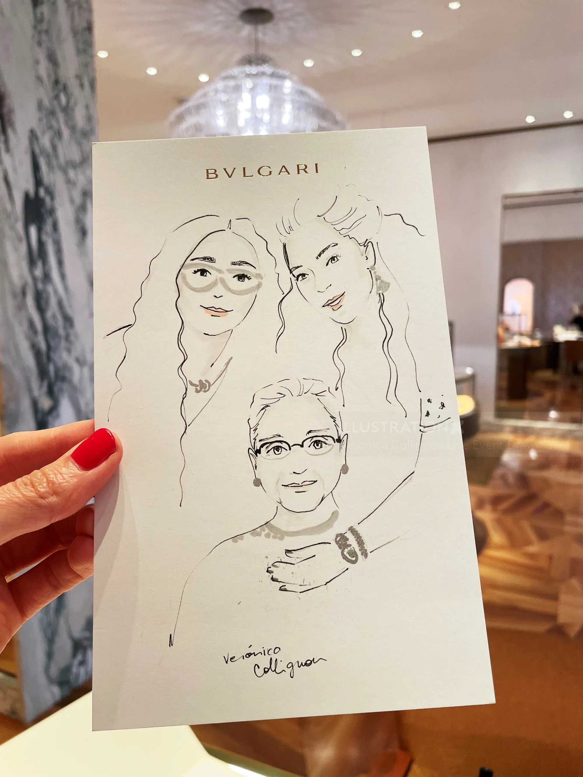 Hand holding a BVLGARI illustration of three faces indoors