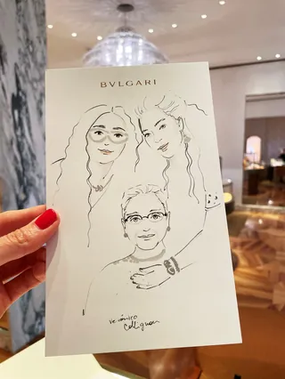Hand holding a BVLGARI illustration of three faces indoors