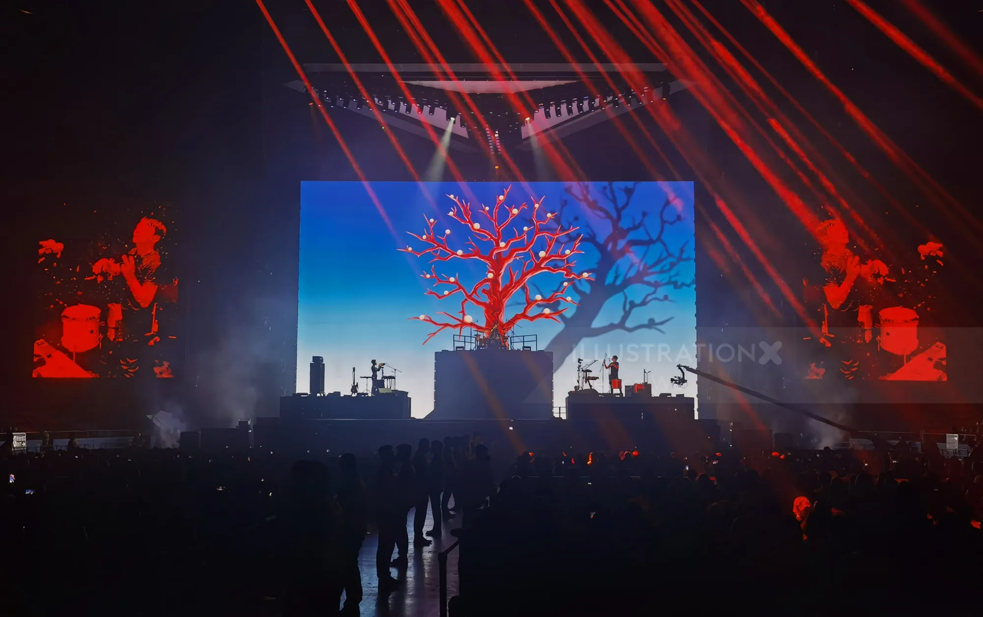 Live concert stage with red tree visuals and band playing by Weston Wei