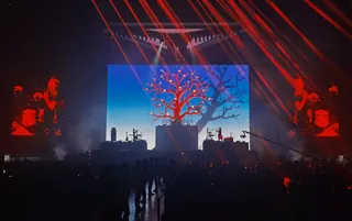 Live concert stage with red tree visuals and band playing by Weston Wei