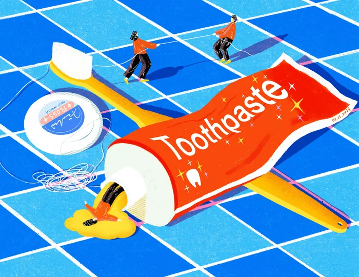 Miniature people cleaning giant toothbrush and toothpaste on blue tiles