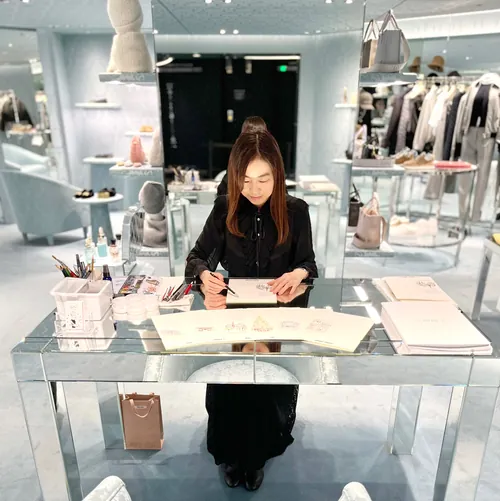 Woman sketching at a glass table in a luxury fashion store
