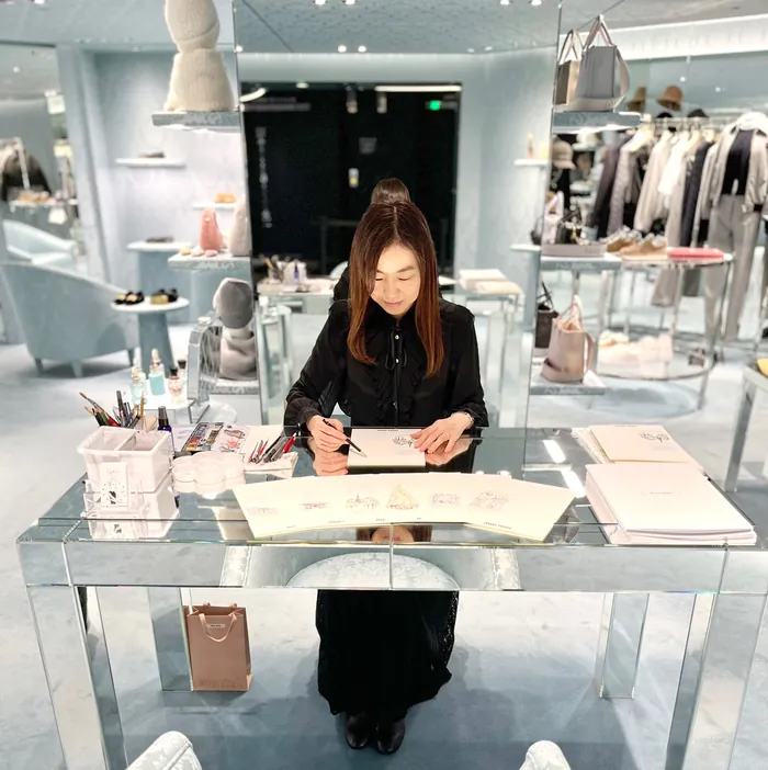 Woman sketching at a glass table in a luxury fashion store