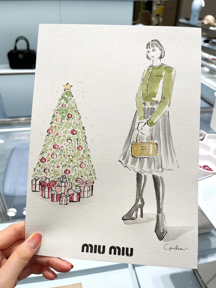 Hand holding fashion illustration with a Christmas tree and woman