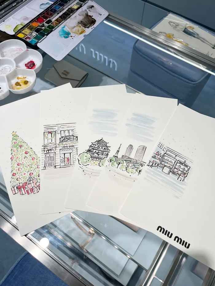 Watercolor sketches of buildings and a Christmas tree on table