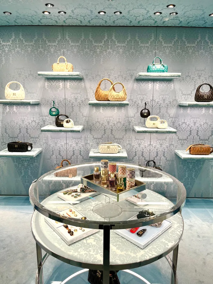 Luxury handbags and accessories displayed on shelves and glass table