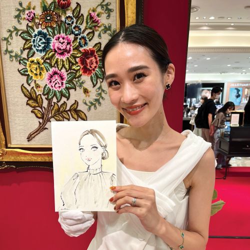 Woman in white holding a portrait sketch at live event