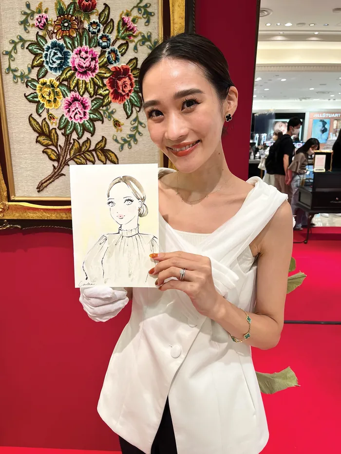 Woman in white holding a portrait sketch at live event