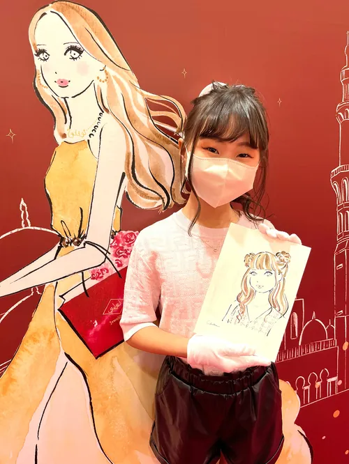 Girl holding a drawing of a fashionable woman at live event