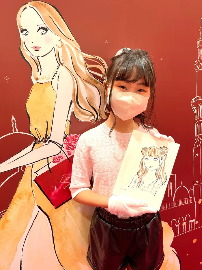 Girl holding a drawing of a fashionable woman at live event