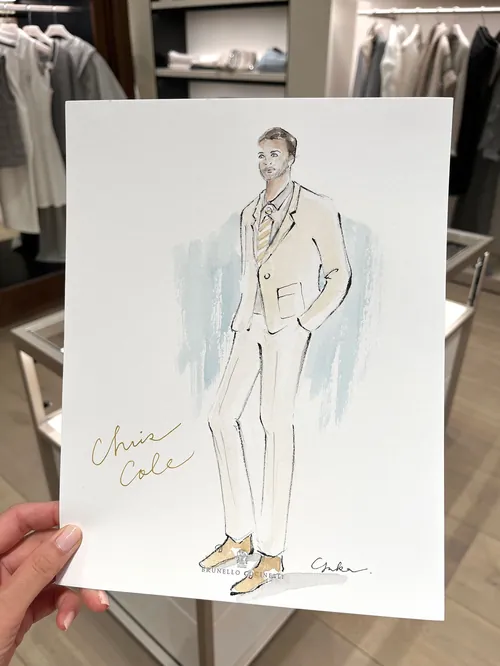 Hand holding fashion illustration of man in beige suit and shoes