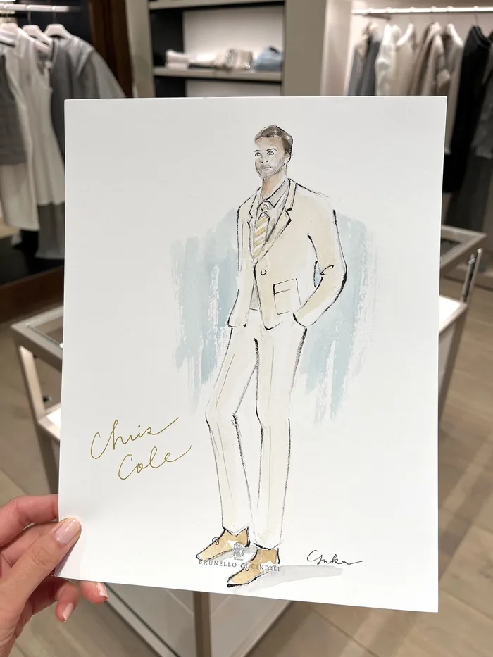Hand holding fashion illustration of man in beige suit and shoes