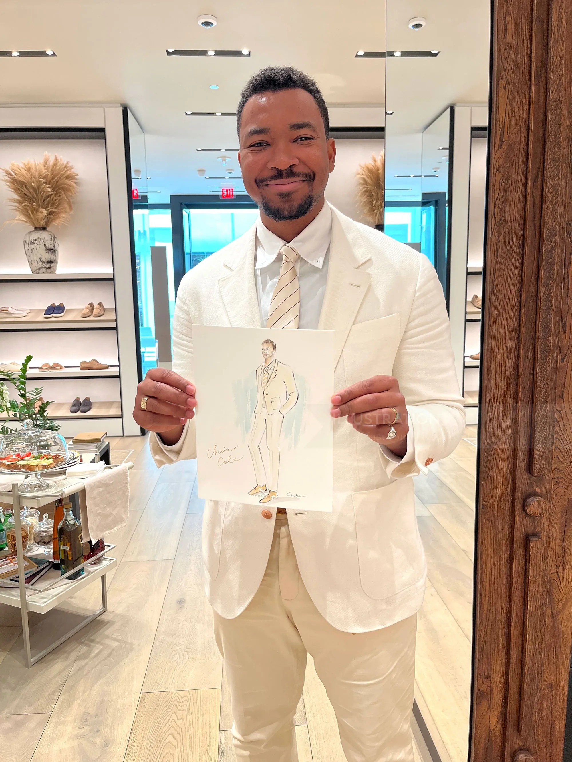 Man in white suit holding fashion sketch in boutique