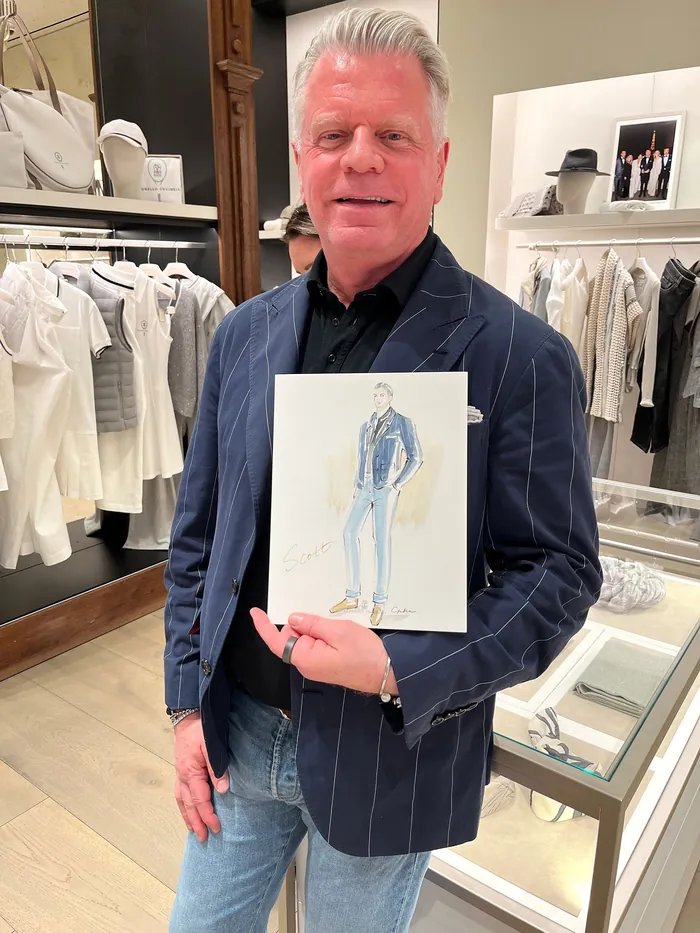 Man holding a fashion illustration in a clothing store