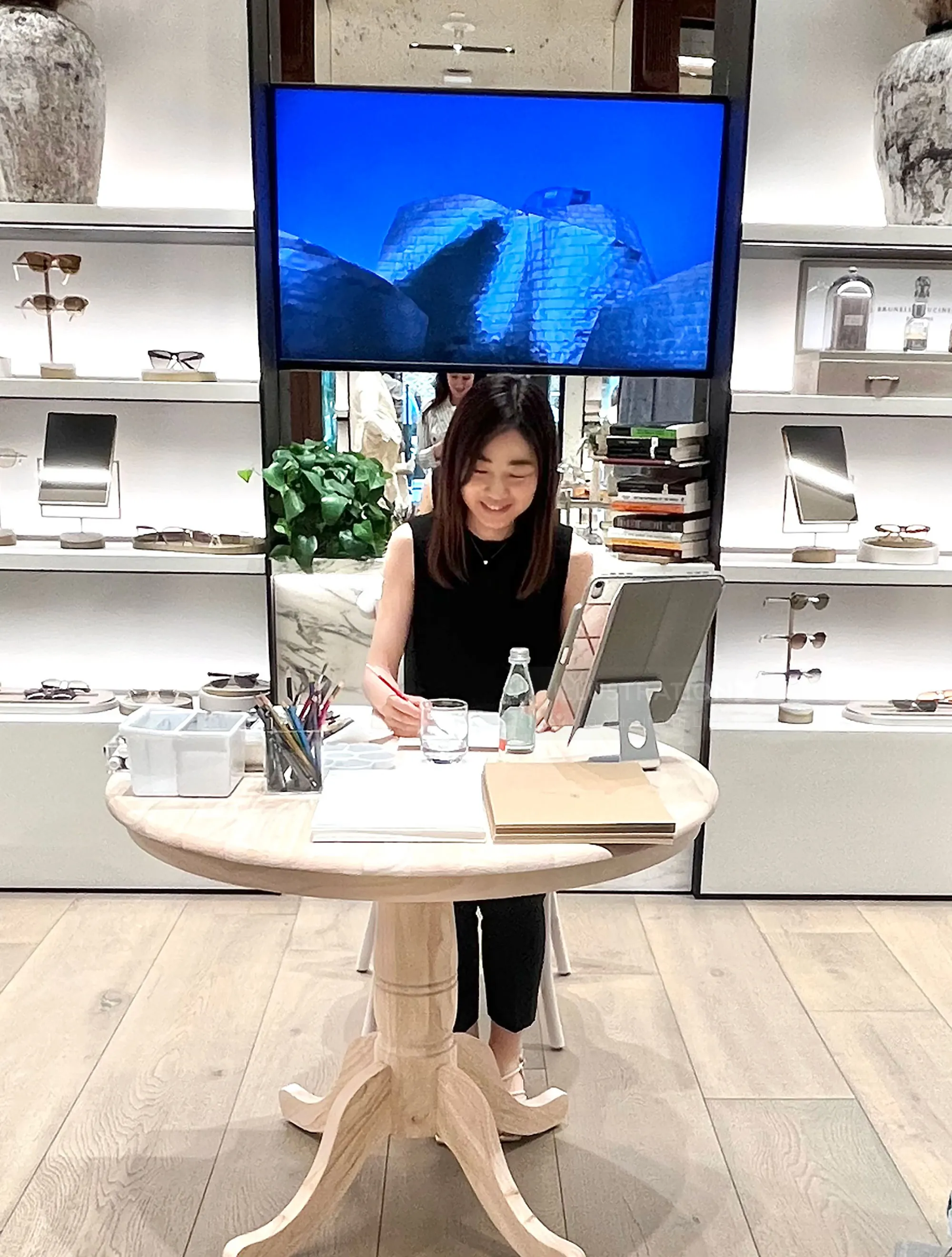 Woman writing at a round table during a live event in a modern store