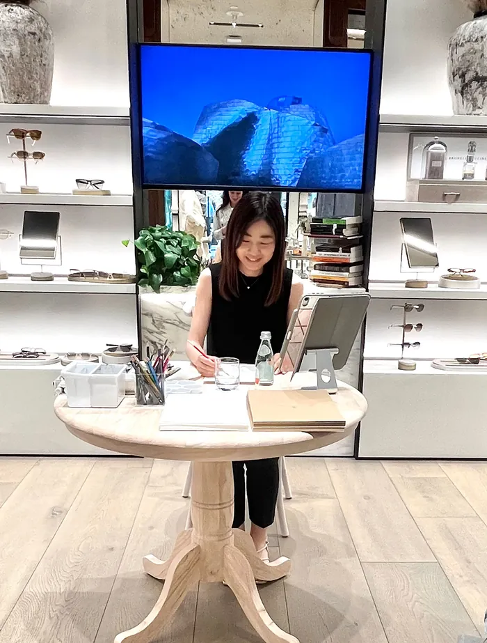 Woman writing at a round table during a live event in a modern store