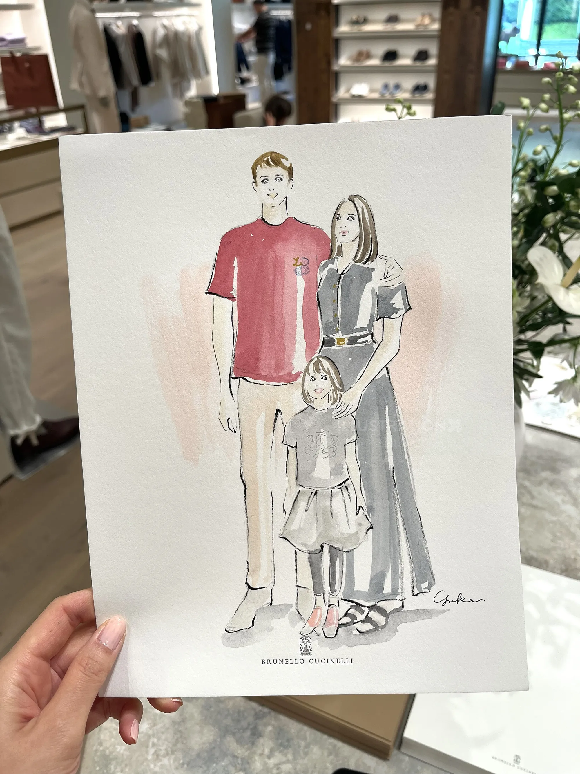 Hand holding fashion illustration of family at Brunello Cucinelli event