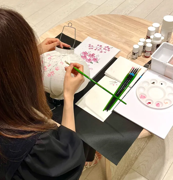 Person painting pink floral design on fabric at art event