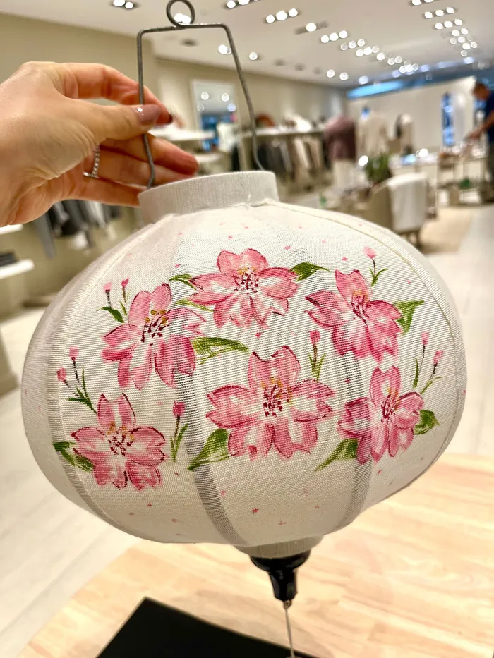 Hand holding white lantern with pink floral design in store