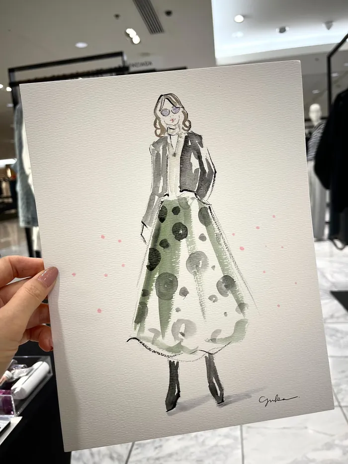 Hand holding fashion illustration of woman in green polka dot skirt